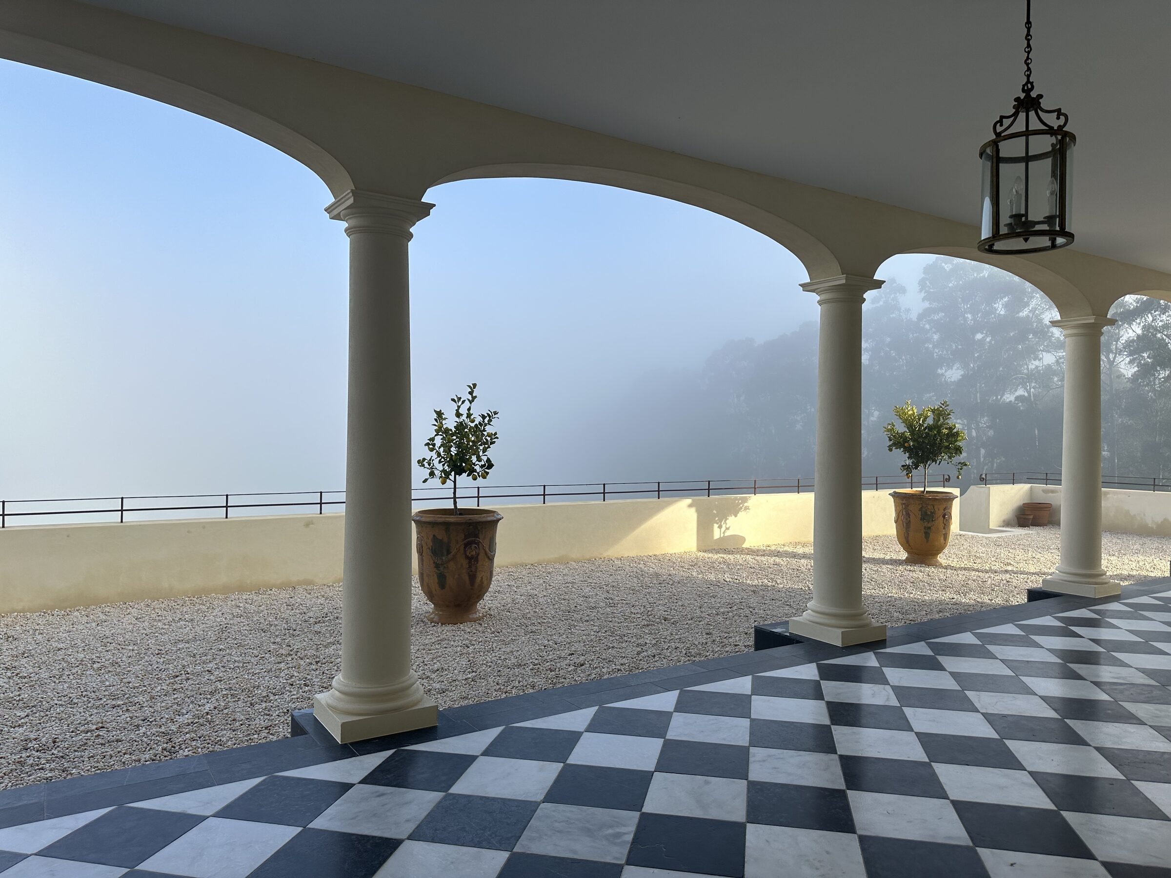 The colonnade at Terre Rouge — arched columns with hanging lanterns and checkerboard floor